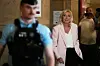 Marine Le Pen kommt im hellen Blazer am Pariser Berufungsgericht an, Polizist im Vordergrund.
