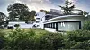 Moderne weiße Villa mit Glasfronten in dichter grüner Hanglage.