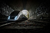 Moderner Zug im dunklen Tunnel mit hellem Licht am Ausgang.