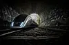 Moderner Zug im dunklen Tunnel mit hellem Licht am Ausgang.