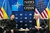 Trump und Selenskyj sitzen sich in Ankara beim NATO-Gipfel vor NATO-, USA- und Ukraine-Flaggen gegenüber.