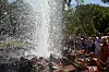 Kaltwasser-Geysir bei Andernach schießt eine hohe Wasserfontäne neben einer Besuchergruppe in die Luft.