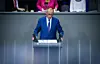 Mann im blauen Anzug spricht am Rednerpult im Bundestag vor sitzenden Abgeordneten.