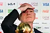 Gianni Infantino bei FIFA-Pressekonferenz, vor ihm eine goldene Trophäe und Sponsorlogos im Hintergrund.