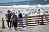 Drei Personen auf einem Holzsteg in Kampen, im Hintergrund Strandkörbe und die Nordsee.