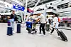 Reisende ziehen Koffer durch den Flughafen vor Check-in-Schaltern.