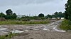 Matschiger Weg durch offene Landschaft unter grauem Himmel