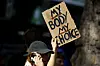 Gegendemonstrantin hält in Köln ein Plakat mit der Aufschrift „My Body, my Choice“ hoch.