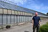 Mann steht vor langem Gewächshaus an sonnigem Tag