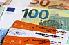 Gesundheitskarten vor Euro-Banknoten als Symbol für Krankenkassenausgaben.
