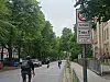 Radfahrer auf Straße vor Schule, daneben Tempo-30- und Schul-Schild am rechten Straßenrand.