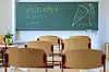 Leere Grundschule mit Tafel „Willkommen in unserer Schule“ und Stühlen im Klassenraum.