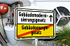 Ortsschild mit Gebäudemodernisierungsgesetz und durchgestrichenem Gebäudeenergiegesetz vor Gasheizung und Wärmepumpe.