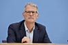 Dr. Gerald Gaß spricht bei der Bundespressekonferenz in Berlin vor blauem Hintergrund.