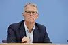 Dr. Gerald Gaß spricht bei der Bundespressekonferenz in Berlin vor blauem Hintergrund.