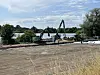 Bagger und Arbeiter an einem Uferstreifen neben einem Gewässer.