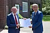 Kulturstaatsminister Wolfram Weimer (parteilos) übergibt Friedhofsgeschäftsführer Carsten Helberg vor Kapelle 13 den Förderbescheid am Parkfriedhof Ohlsdorf.