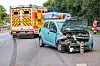 Beschädigter Kleinwagen mit offener Motorhaube vor einem Rettungswagen auf nasser Straße