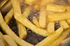 Pommes werden in einem Imbiss in Pflanzenöl frittiert.