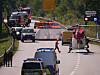 Rettungskräfte und Einsatzfahrzeuge sichern eine Unfallstelle auf einer kurvigen Landstraße ab.
