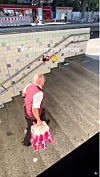 Mann mit Einkaufstüten auf Treppe an U-Bahn-Station; an der Wand steht „Mitarbeiter des Monats“.