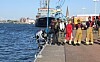 Einsatzkräfte stehen an einer Hafenmole neben einem Boot am Wasser.