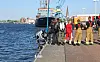 Einsatzkräfte stehen an einer Hafenmole neben einem Boot am Wasser.