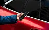 Hand fotografiert Kratzer am roten Mietwagen mit dem Smartphone.