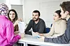Eltern und Lehrkräfte besprechen am Tisch Fragen zum Schulalltag im Klassenzimmer.