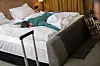 Mann liegt krank im Hotelbett, Koffer im Zimmer, Urlaub wirkt unterbrochen.