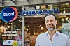Mann vor dem Eingang eines Budni-Drogeriemarkts mit blau-rotem Logo.