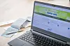 Laptop mit geöffneter ELSTER-Startseite, daneben liegen Papierunterlagen auf einem Tisch.