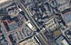 Dichte Stadtbebauung mit Kreuzung, Bahntrasse, Parkplätzen und Gebäuden aus der Luft.