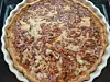 Goldbraune Quiche mit geriffeltem Rand in einer runden Backform, von oben gesehen.