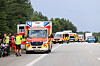 Rettungswagen und Einsatzkräfte an einer Landstraße, weitere Einsatzfahrzeuge stehen in Reihe am Straßenrand.