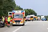 Rettungswagen und Einsatzkräfte an einer Landstraße, weitere Einsatzfahrzeuge stehen in Reihe am Straßenrand.
