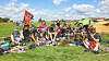 Gruppe von Punks sitzt auf einer Wiese. Im Hintergrund sind Zelte zu sehen.