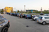Ein Supermarktparkplatz mit mehreren geparkten Autos und einigen Menschen.