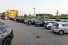 Ein Supermarktparkplatz mit mehreren geparkten Autos und einigen Menschen.