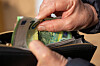 Seniorin steckt Euro-Banknoten in ein offenes Portemonnaie. (Symbolbild)