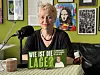 Frau an einem Tisch vor Mikrofon und buntem Hintergrund.