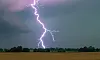 Blitz schlägt bei Gewitter über offenem Feld ein.