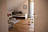 Kinderzimmer mit Bett, Teppich, Holzspielzeug und Tageslicht in den Fertighauswelten Langenhagen.