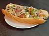 Belegtes Baguette mit Salat und Gemüse auf weißem Teller