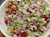 Bunter Mischsalat in einer Schale mit Eisbergsalat, Tomaten und Schinkenstücken.