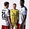 Drei Fußballspieler des Hamburger SV in Trikots vor hellem Hintergrund.