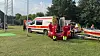 Einsatzkräfte arbeiten neben Rettungswagen und Einsatzfahrzeug an einer abgesperrten Stelle im Grünen.