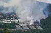 Dichter Rauch über Reihenhäusern in Krokstadelva bei Drammen; Flammen sind im Wohngebiet sichtbar.