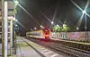 Nachts hält ein Zug am Bahnhof Ettlingen-Bruchhausen, die Gleise und Bahnsteige sind beleuchtet.