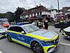 Polizei mit Einsatzfahrzeugen vor einem Restaurant; Einsatzkräfte und Passanten an einer regennassen Straße.
